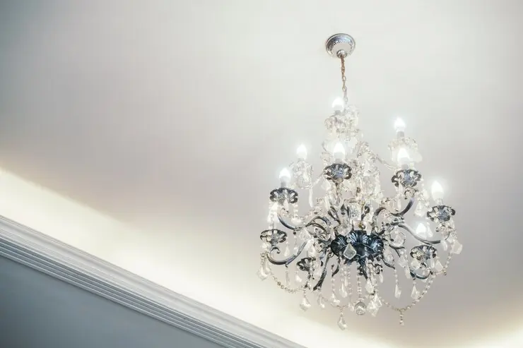 Lustră de cristal pe un tavan alb și neted, cu lumină ascunsă pe contur
